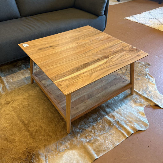 Wooden coffee table in a living room setting with a sofa and rug.