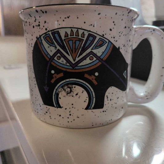 Speckled mug with a decorative design on a white surface