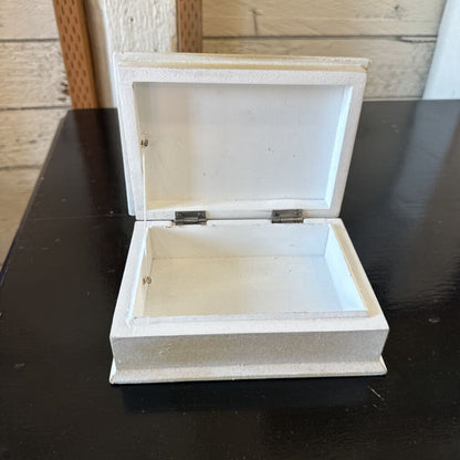 White jewelry box with a lid on a dark surface