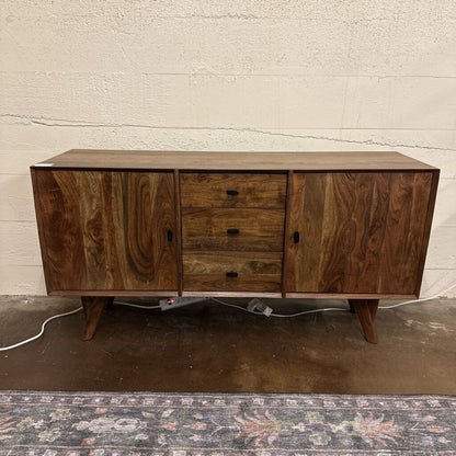 Wooden sideboard with drawers against a white brick wall.