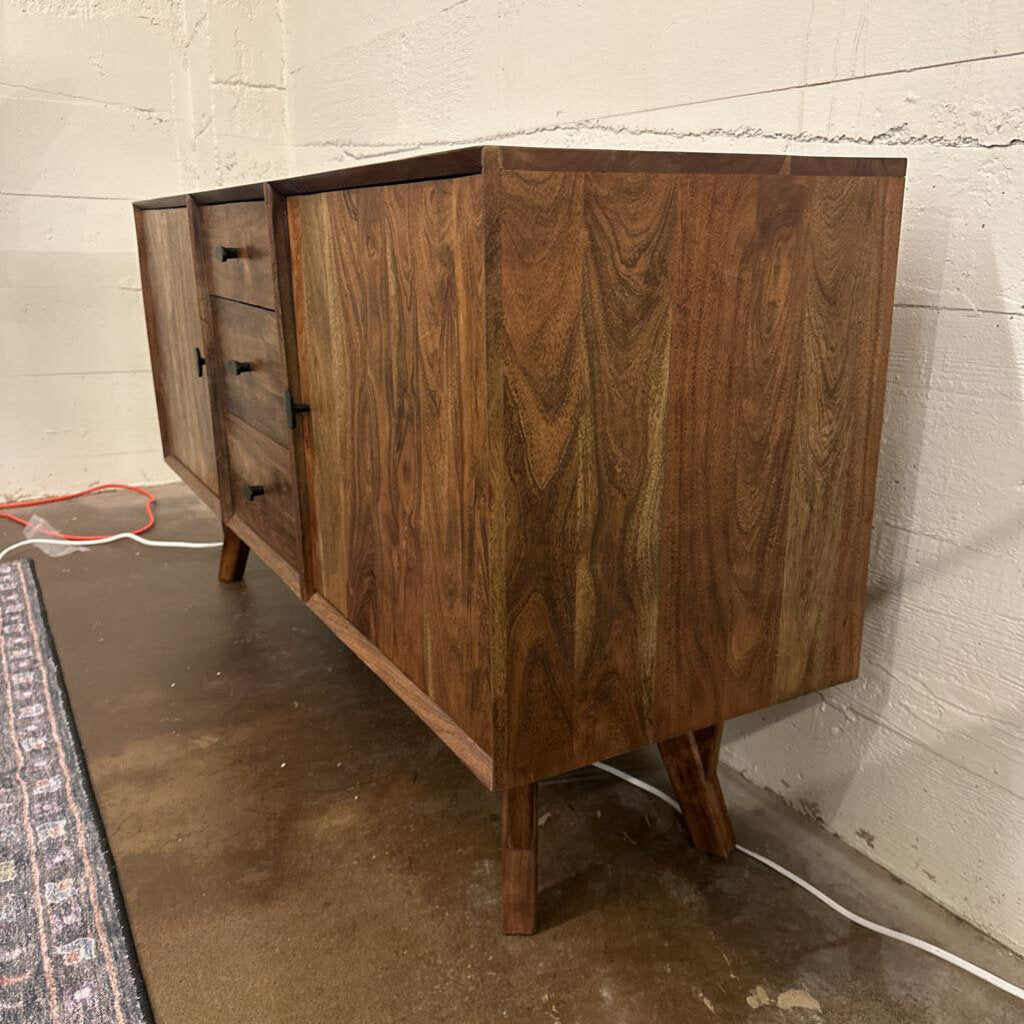 Wooden dresser against a white brick wall.