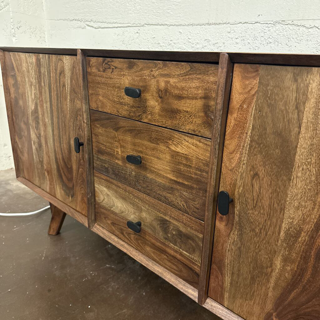 Wooden sideboard with drawers and doors on a concrete floor.