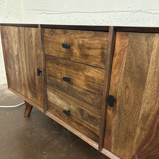 Wooden sideboard with drawers and doors on a concrete floor.