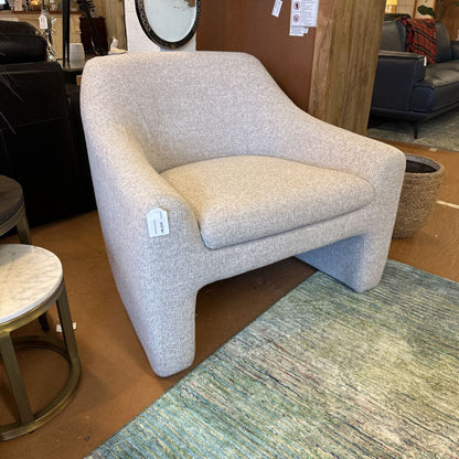 Beige armchair in a showroom setting with a tag on it