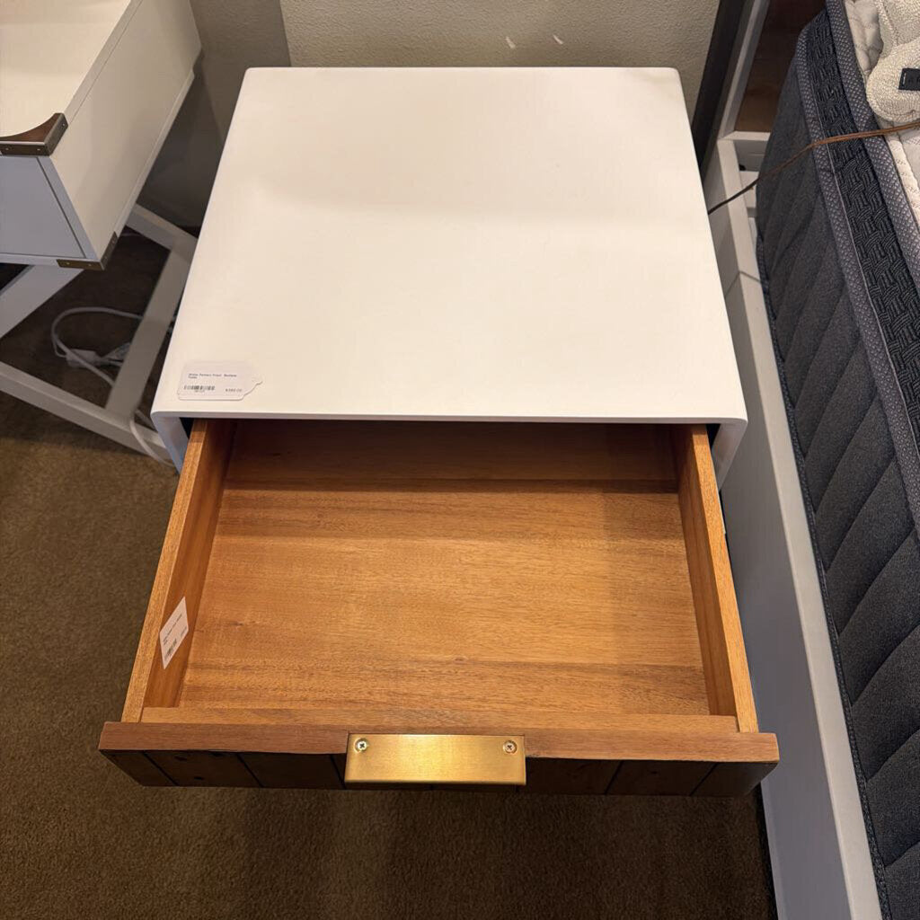 Open wooden drawer with white surface above, possibly in a furniture store.