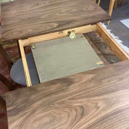 Wooden table with a drawer pulled out, showing a gray mat inside.