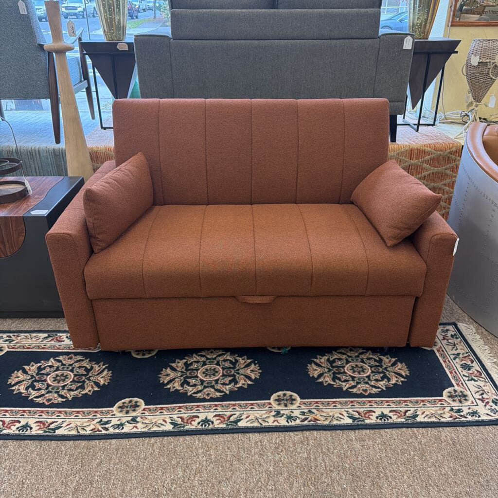 Brown sofa with cushions on a patterned rug in a room setting