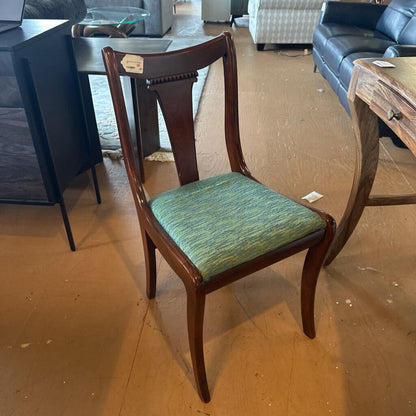 Wooden chair with a green cushion on a wooden floor in an indoor setting