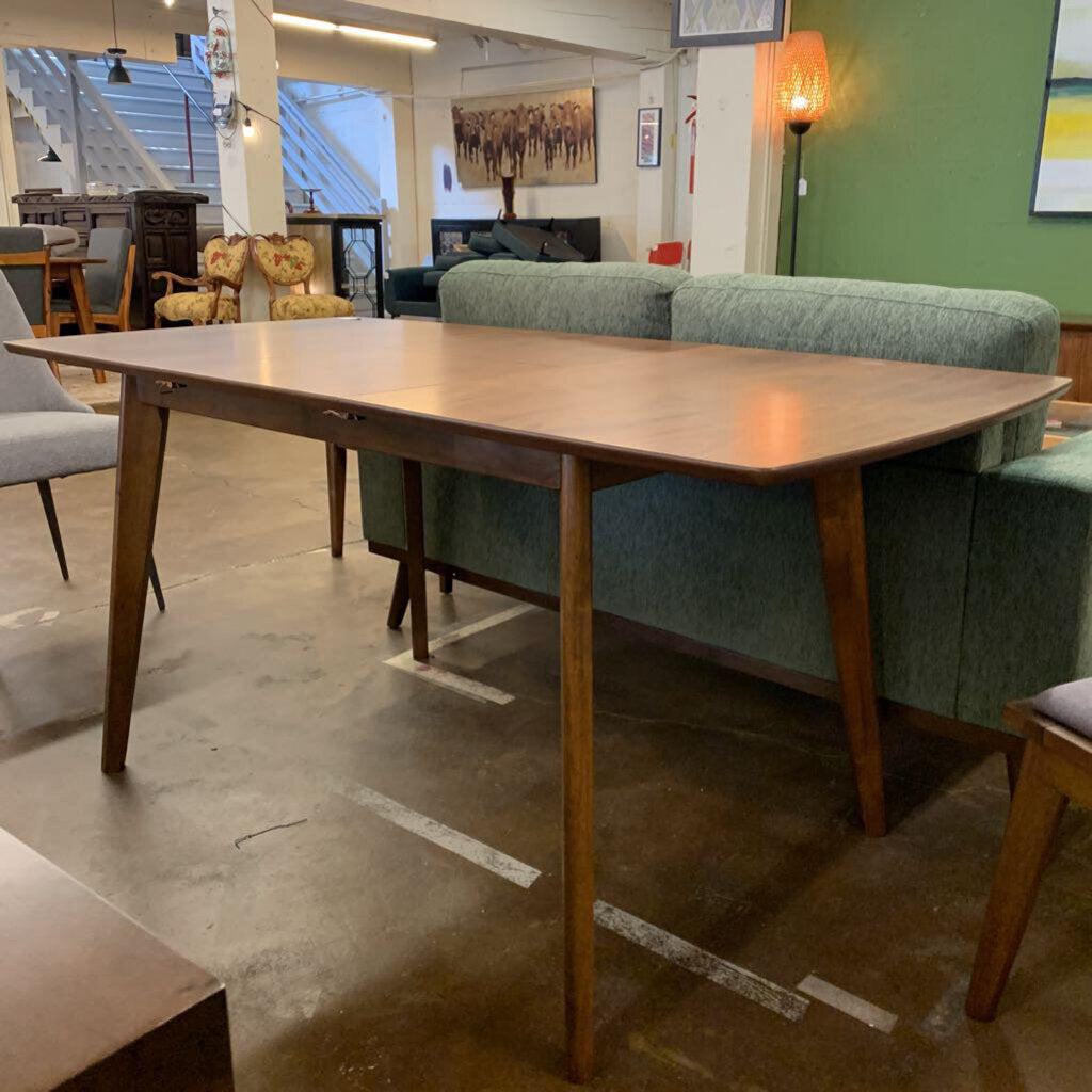 Wooden dining table in a room with green sofa and chairs.