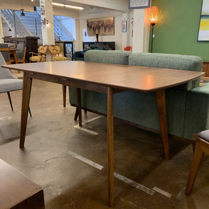 Wooden dining table in a room with green sofa and chairs.