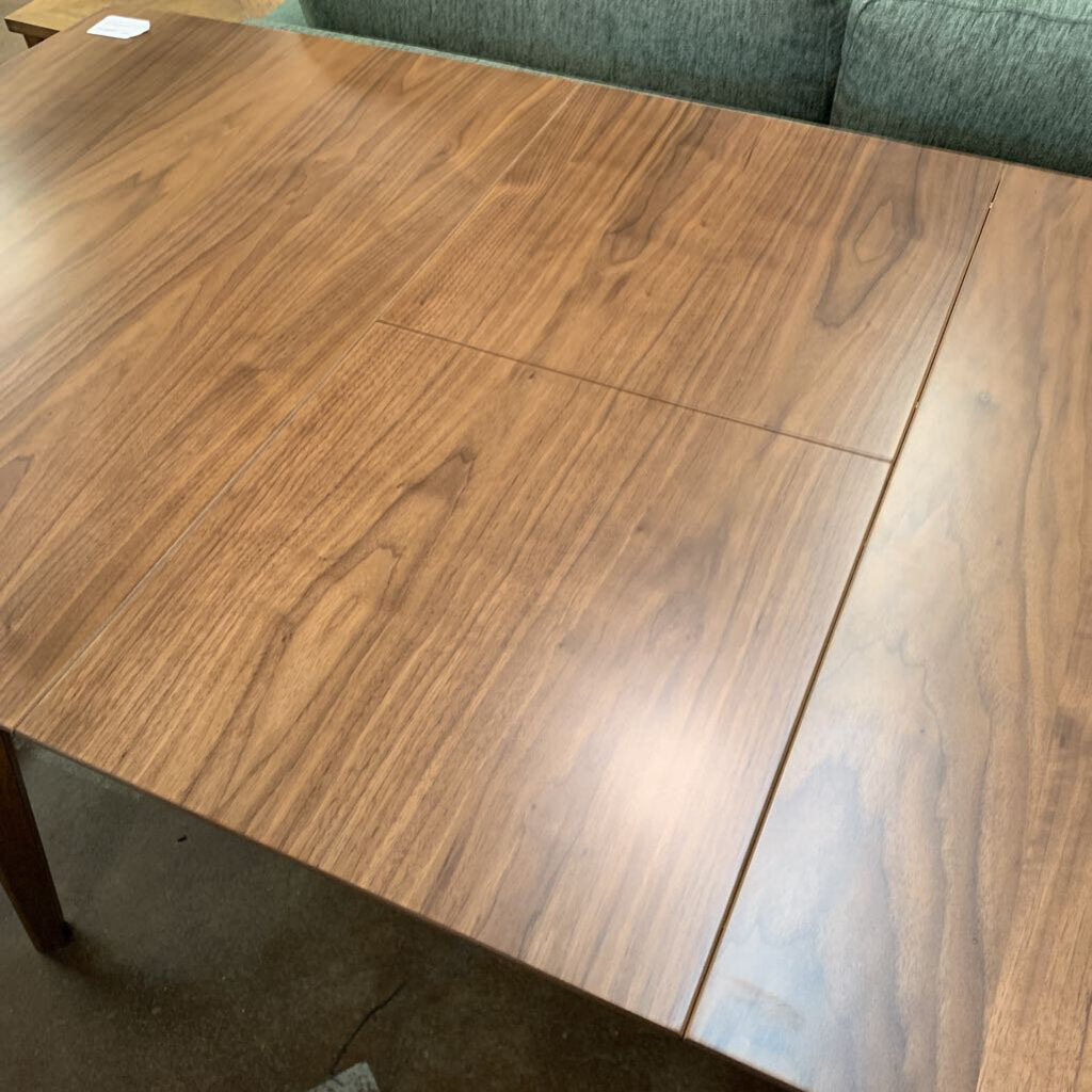 Wooden dining table with a green sofa in the background