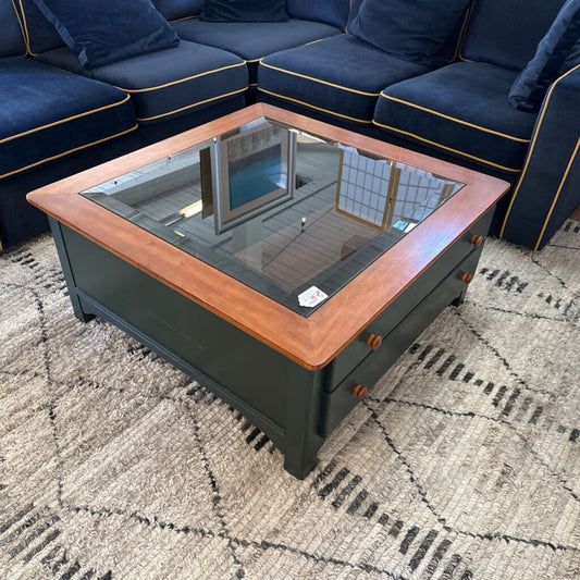 Wooden coffee table with glass top in a living room setting