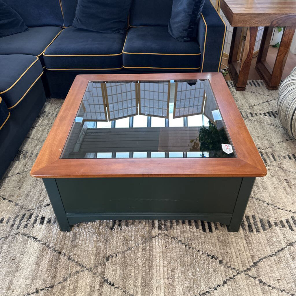 Coffee table with wooden frame and glass top in a living room setting