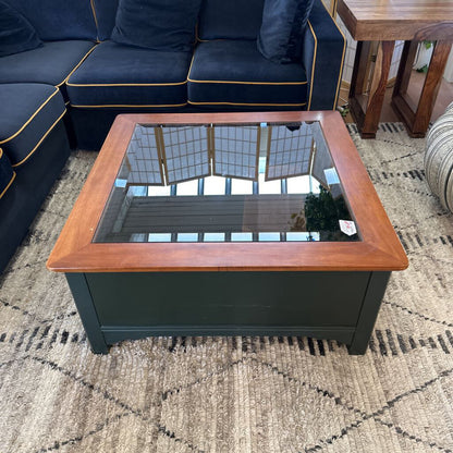 Coffee table with wooden frame and glass top in a living room setting