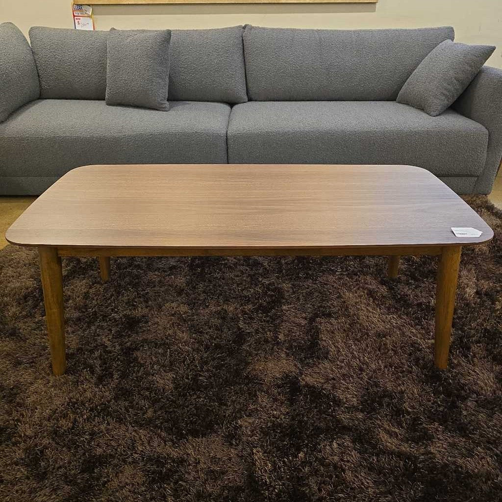 Gray sectional sofa with a wooden coffee table on a brown carpet