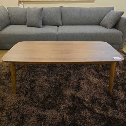 Gray sectional sofa with a wooden coffee table on a brown carpet