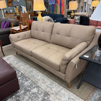 Beige sofa in a room with various furniture and decor items.