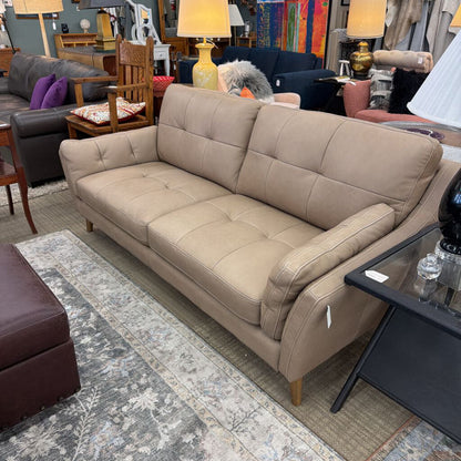 Beige sofa in a furniture store setting with various items in the background