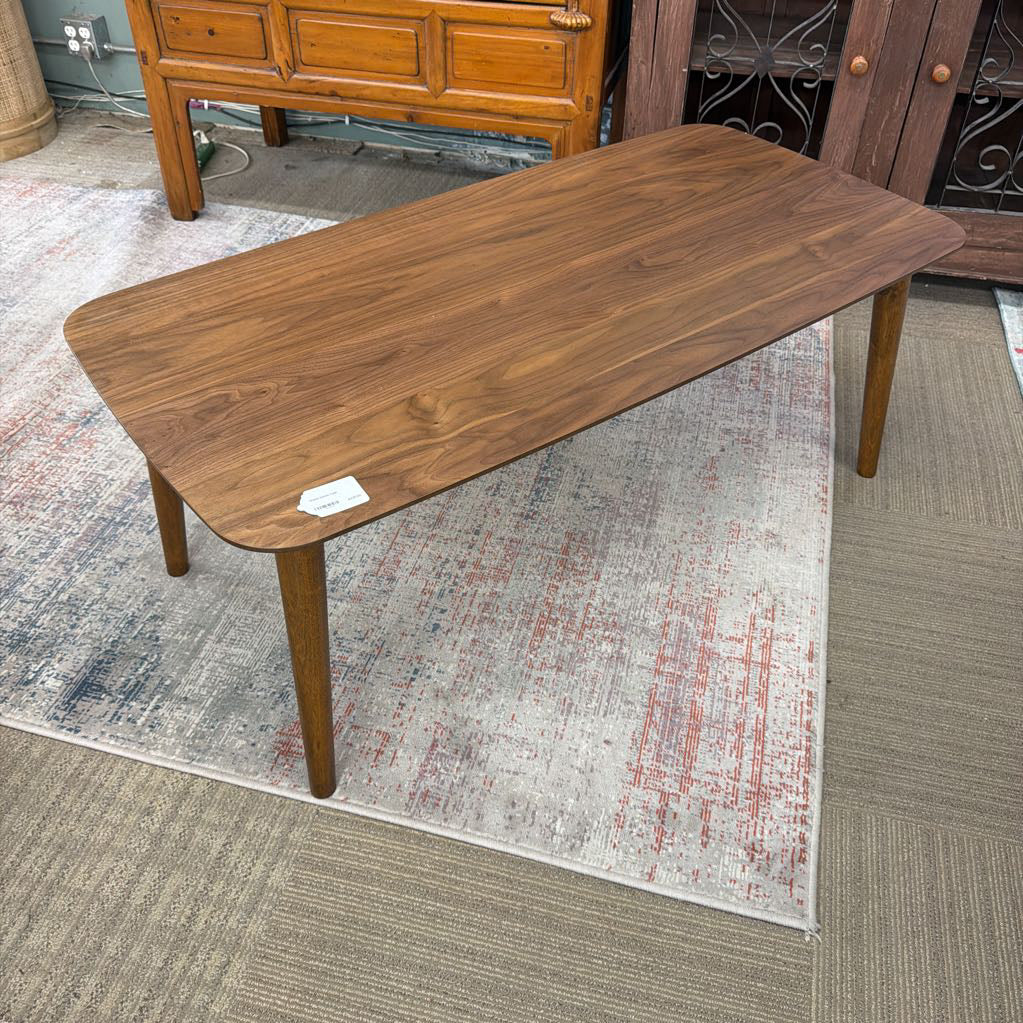 Wooden coffee table on a patterned rug with a wooden cabinet in the background.