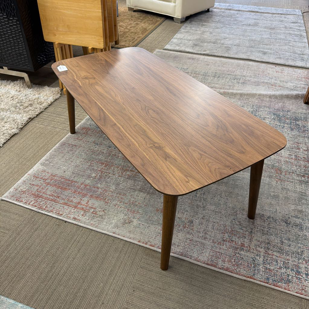 Wooden coffee table on a patterned rug with furniture in the background