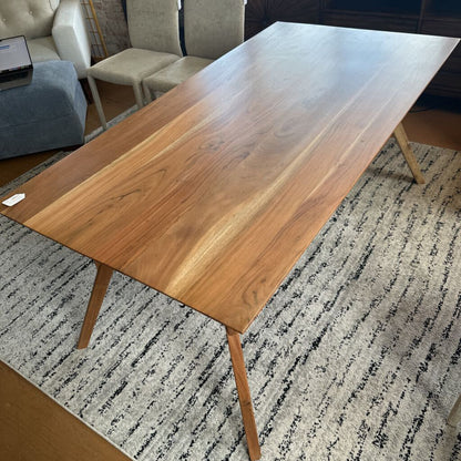 Wooden dining table in a room with chairs and a rug.