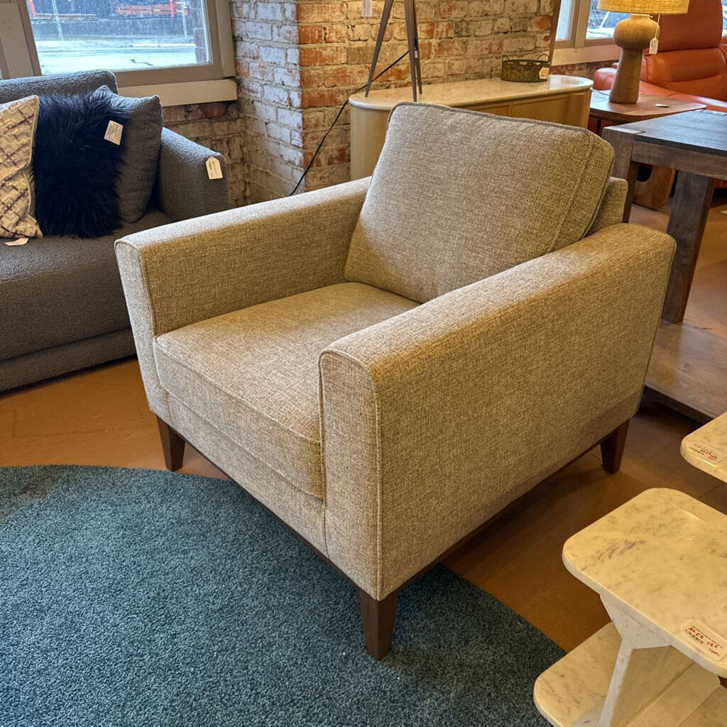 Beige armchair in a room with a brick wall and other furniture.