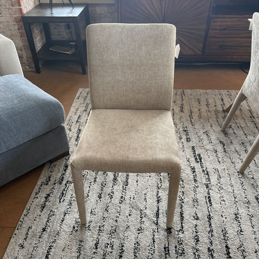 Beige chair on a patterned rug in a room with furniture