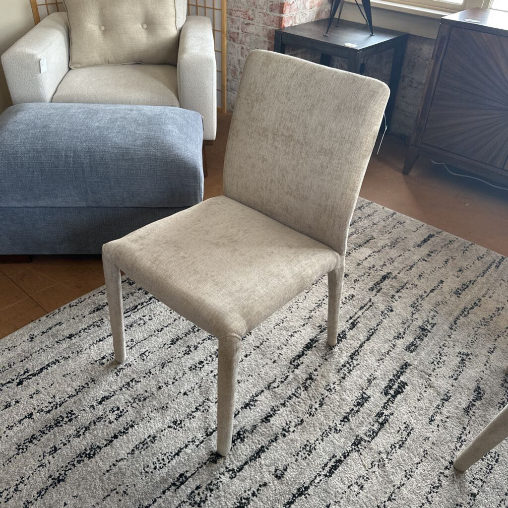 Beige chair on a patterned rug in a room with furniture