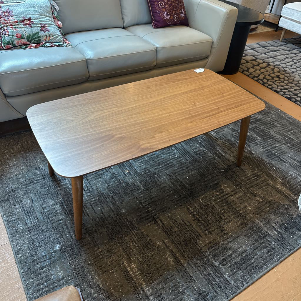 Wooden coffee table in a living room setting with a sofa and rug.