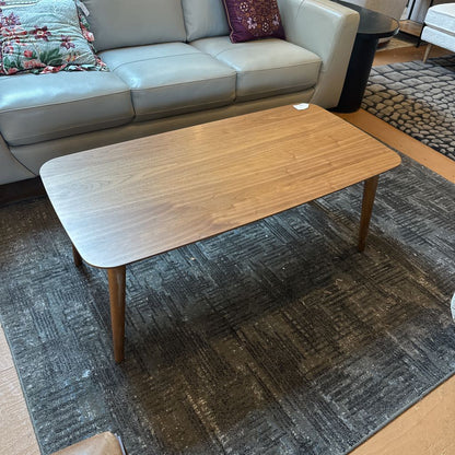 Wooden coffee table in a living room setting with a sofa and rug.