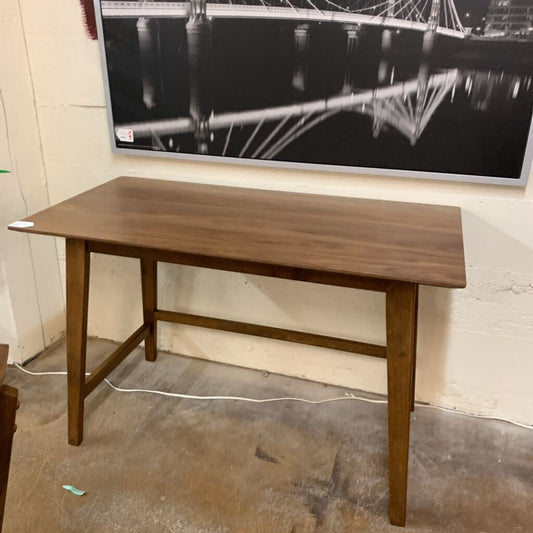 Wooden table in a room with a large screen displaying a black and white image of a bridge.