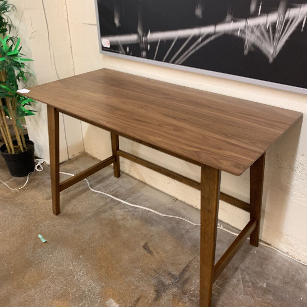 Wooden desk in a room with a television and plant