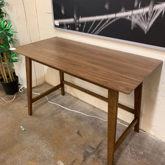 Wooden desk in a room with a television and plant