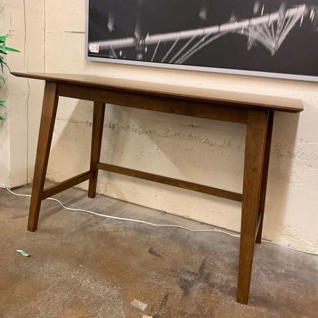 Wooden table against a wall with a television mounted on it