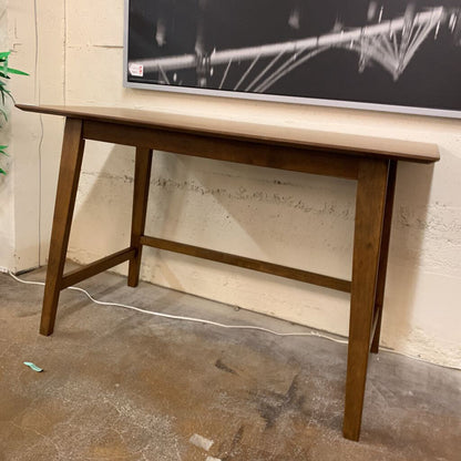 Wooden table against a wall with a television mounted on it