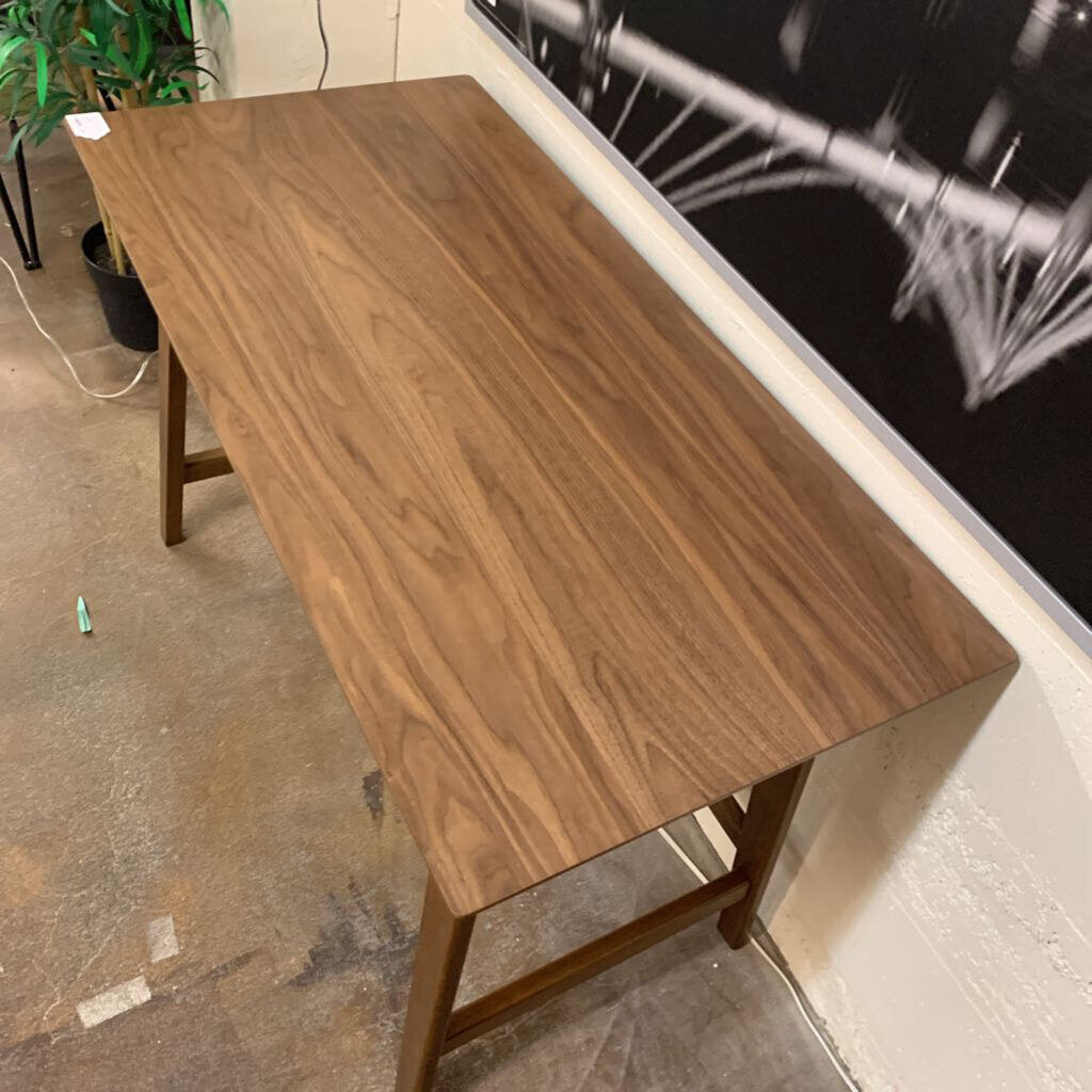 Wooden table in a room with a plant and wall art.