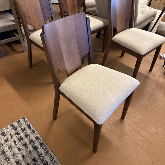 Dining chairs with wooden frames and upholstered seats in a showroom setting.