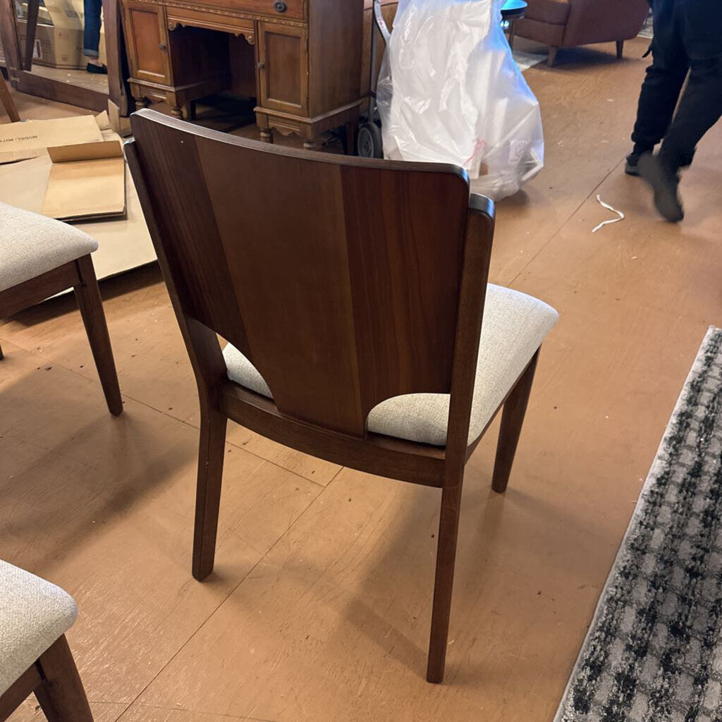 Wooden chair with white cushion on a wooden floor, surrounded by furniture and boxes.