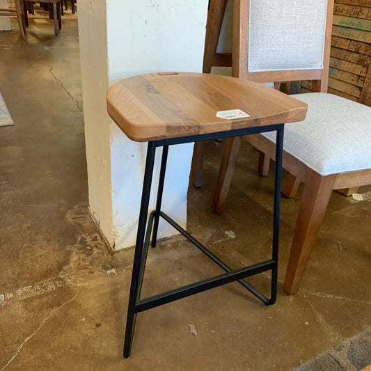 Wooden stool with black metal legs on a tiled floor