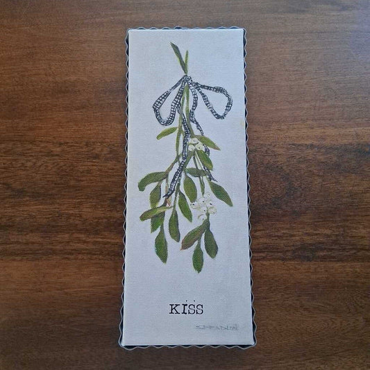 Decorative box with floral design and 'KISS' text on a wooden surface