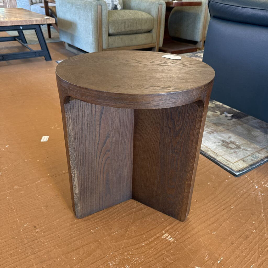 Wooden side table on a brown floor with furniture in the background