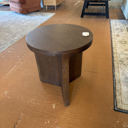 Wooden side table on a wooden floor with rugs and furniture in the background