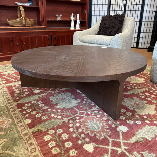 Wooden coffee table in a room with a red patterned rug and wooden furniture.
