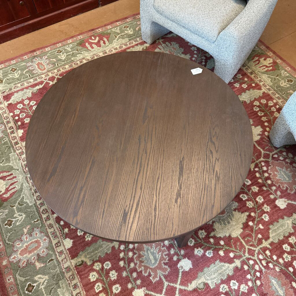Round wooden table on a patterned rug with a chair partially visible