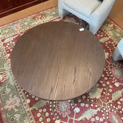 Round wooden table on a patterned rug with a chair partially visible