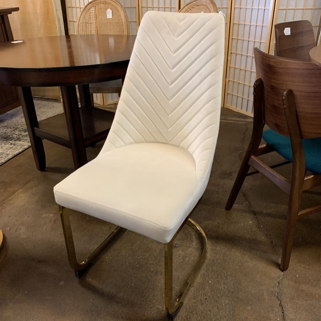 White upholstered chair with gold frame in a showroom setting