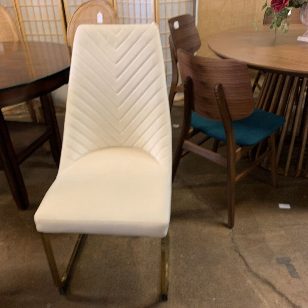White chevron-patterned chair in a furniture store setting with other chairs and tables.