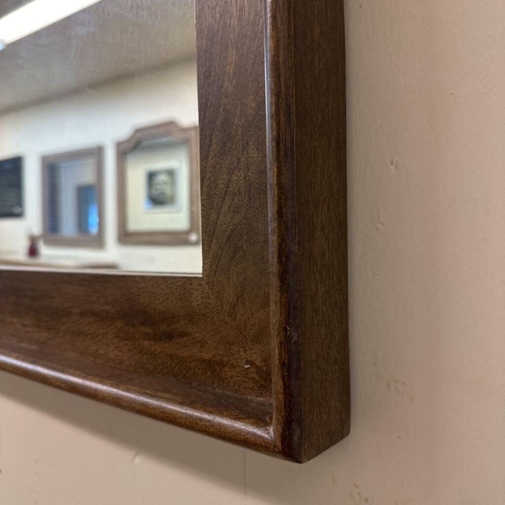 Close-up of a wooden-framed mirror on a wall.