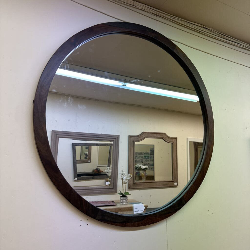 Round wooden-framed mirror on a wall with reflections of other mirrors.