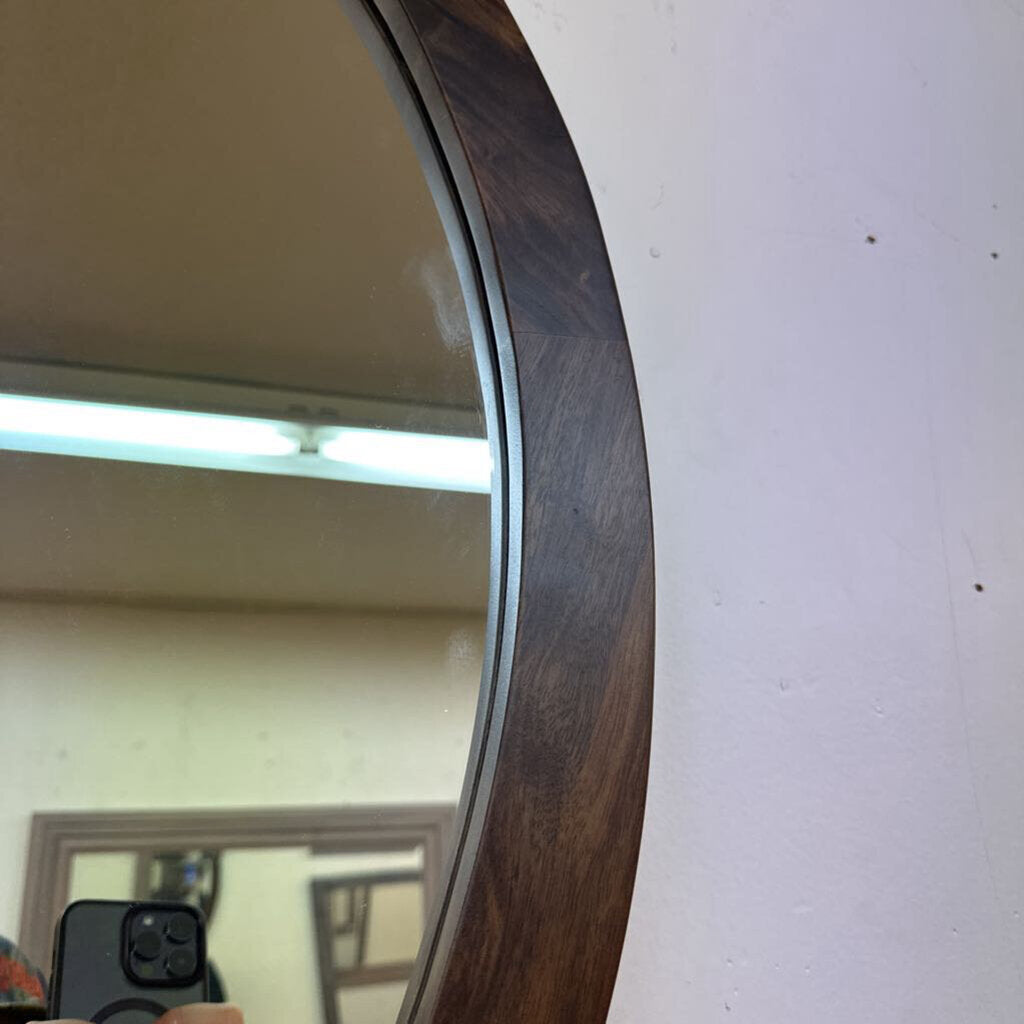 Round mirror with a wooden frame on a white wall